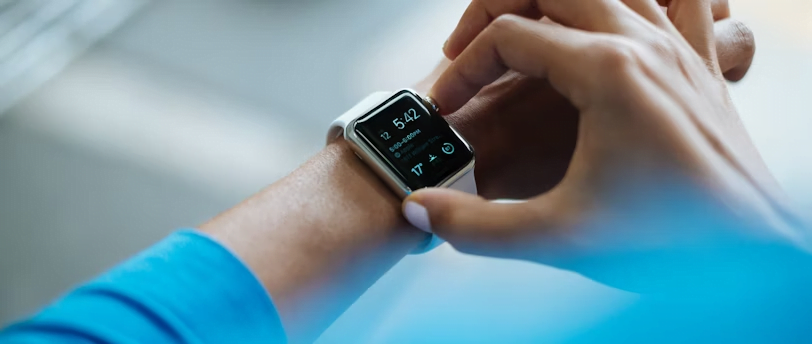 A person wearing a blue shirt interacts with a smartwatch displaying various icons and the time 5:42, seamlessly integrating effective time management into their daily routine.